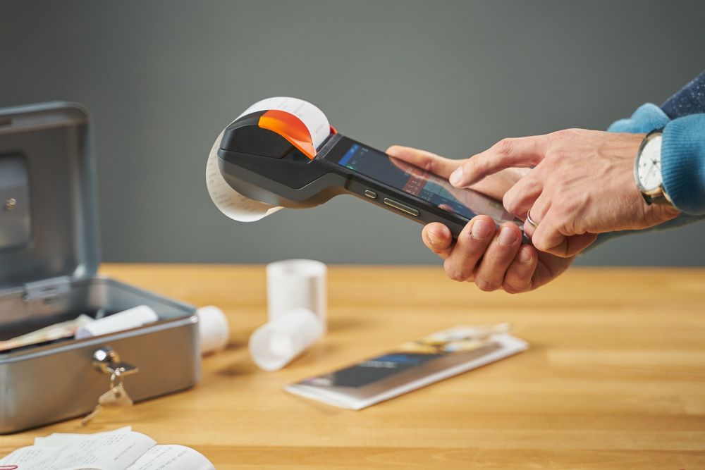Retail employee using a handheld POS terminal to print a fiscal receipt, illustrating EET 2.0 sales recording and digital transaction compliance requirements in the Czech Republic.